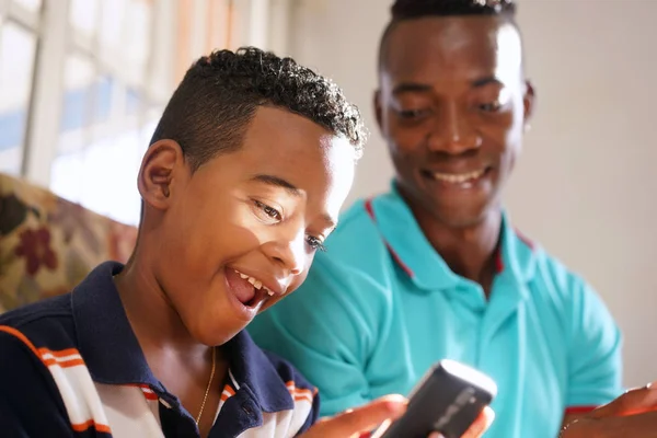 Pai ensinando tecnologia de telefone móvel para filho em casa — Fotografia de Stock