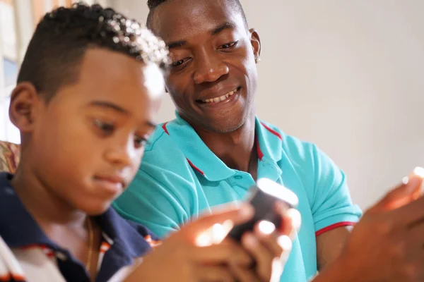 Молодий чоловік пояснює мобільний телефон Інтернет хлопчику вдома — стокове фото