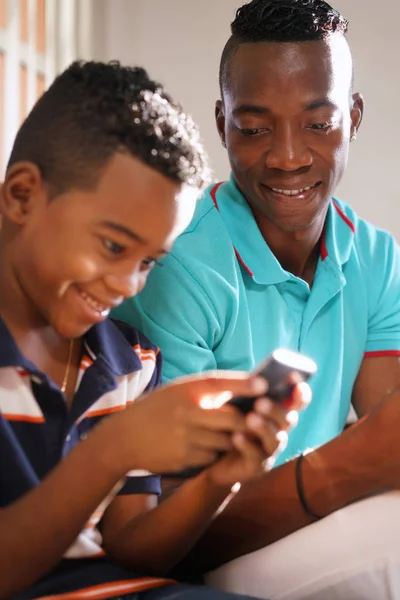 Joven hombre explicando el Internet del teléfono móvil al hijo en casa —  Fotos de Stock