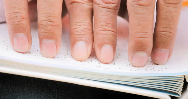 Пальцы мигающего человека трогают страницу в книге Брайля — стоковое фото
