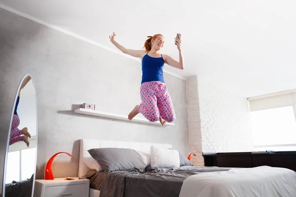 Dobry nowiny pod kątem szczęśliwy młoda kobieta dziewczyna skoki na łóżku — Zdjęcie stockowe