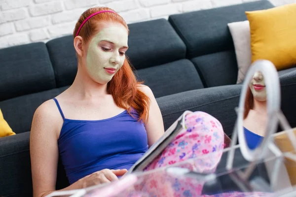 Tiener met schoonheid masker lezing Magazine en ontspannen — Stockfoto