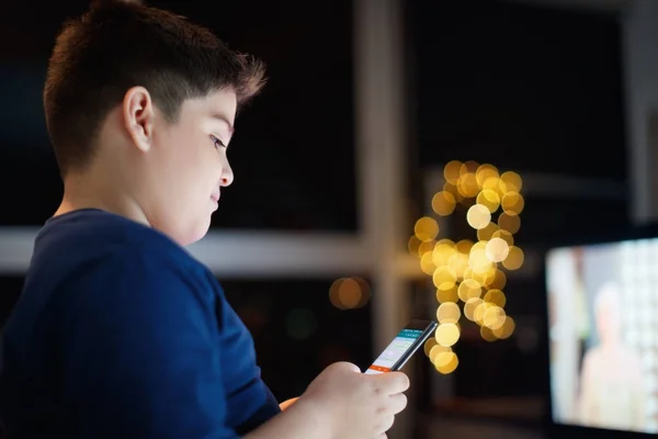 Menino não atendido conversando e digitando no telefone celular à noite — Fotografia de Stock