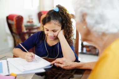 Yaşlı kadın küçük kız yapıyor okul ev ödevi yardım