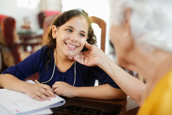 Bejaarde vrouw helpen weinig meisje doen School huiswerk — Stockfoto