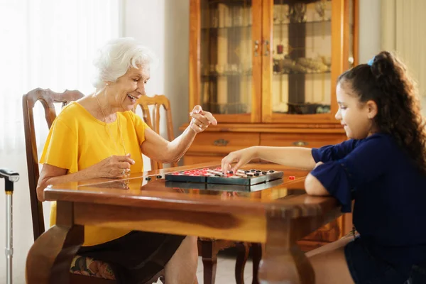 할머니 재생 체커 보드 게임 손녀와 함께 집에서 — 스톡 사진