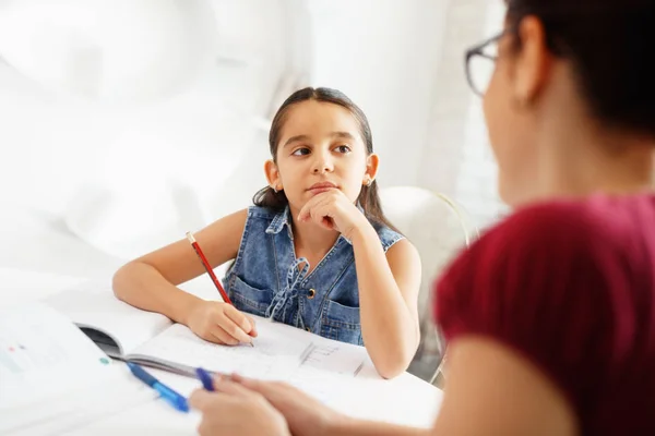 Spansktalande mor hjälpande flicka gör skolan läxor hemma — Stockfoto