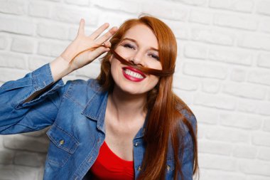 Genç Kızıl saçlı kadının tuğla duvar yüz ifadeleri