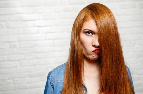 Genç Kızıl saçlı kadının tuğla duvar yüz ifadeleri — Stok fotoğraf