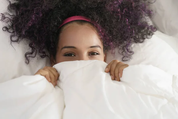 Bella felice ispanico giovanissima svegliarsi e sorridere sotto copertura — Foto Stock