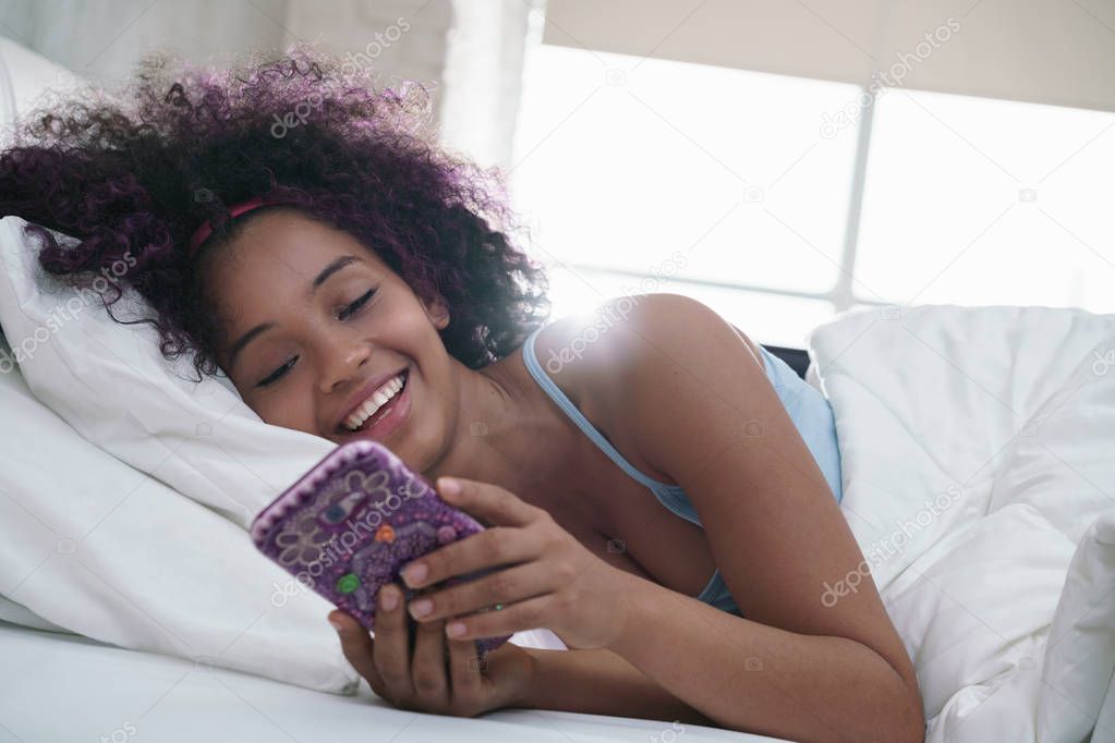 Teen Using Mobile Telephone For Chat In Bed At Home