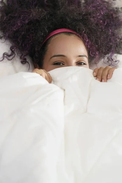 Bella felice ispanico giovanissima svegliarsi e sorridere sotto copertura — Foto Stock