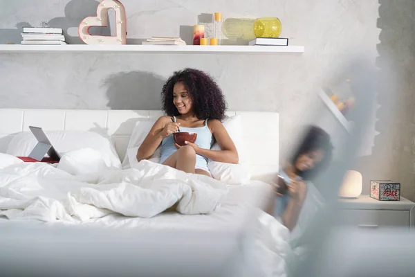 Adolescente mangiare colazione guardando commedia spettacolo a letto — Foto Stock