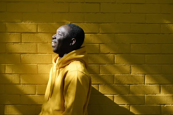 Africano joven sonriendo con amarillo pared en fondo — Foto de Stock