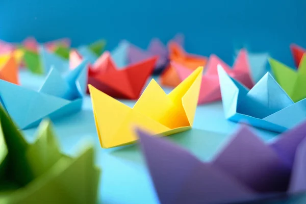 Flota autentycznych Origami Łodzie na niebieskim tle — Zdjęcie stockowe