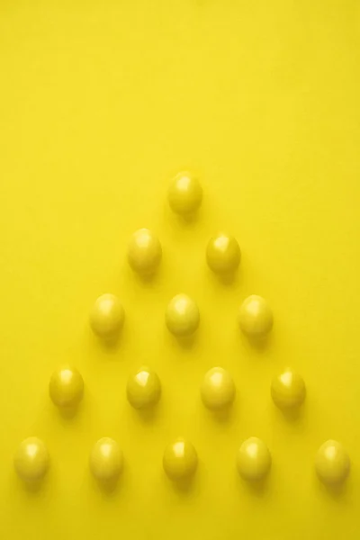 Padrão de ovos de galinha em forma de pirâmide contra fundo amarelo — Fotografia de Stock