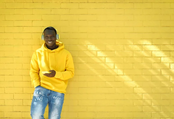 Africano giovane ascolto musica pendente su giallo parete — Foto Stock