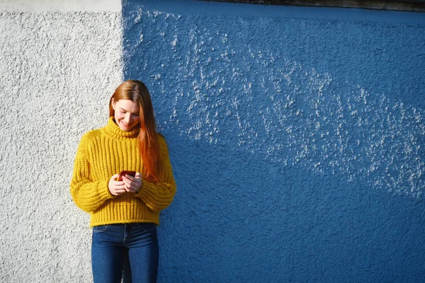 Mladý ryšavý žena odesílání textové zprávy s telefonem venkovní — Stock fotografie