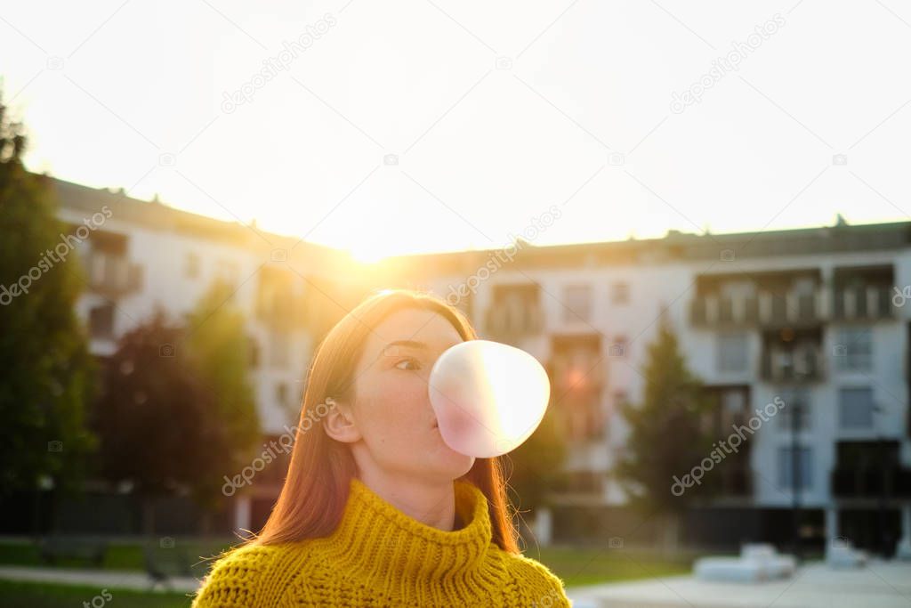 Young Woman Chewing Gum And Making Big Balloon