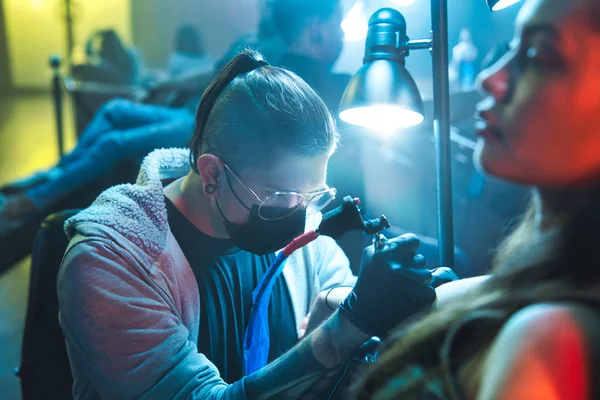 Jonge vrouw het krijgen van tatoeages in schoonheidssalon met tatoeëerder werken — Stockfoto