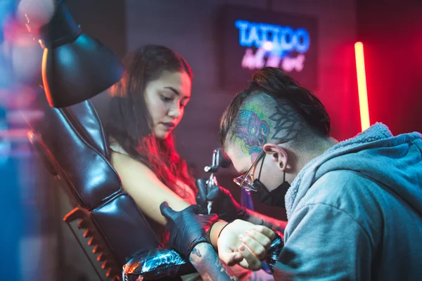 Молода жінка отримує татуювання в салоні краси з татуюванням Робота — стокове фото