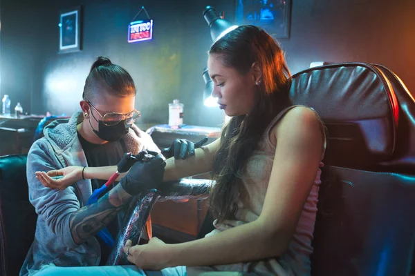 Mladá žena získávání tetování v salónu krásy s tetováním pracovní — Stock fotografie