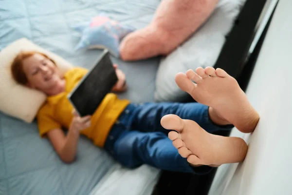 Kleines Rotschopfmädchen sieht Cartoons zu Hause mit Tablet — Stockfoto