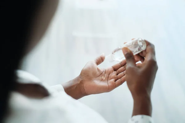 Афроамериканка дезинфицирует кожу с помощью средства для дезинфекции рук — стоковое фото