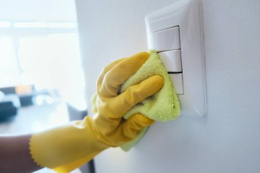 Person With Gloves Disinfecting Light Switches Using Sanitizer clipart