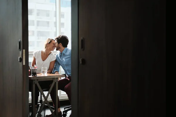 Dois colegas de trabalho sentados na mesa do escritório e beijando — Fotografia de Stock