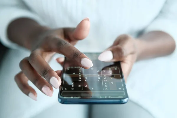 Negro mujer jugando sudoku en teléfono para cerebro entrenamiento —  Fotos de Stock