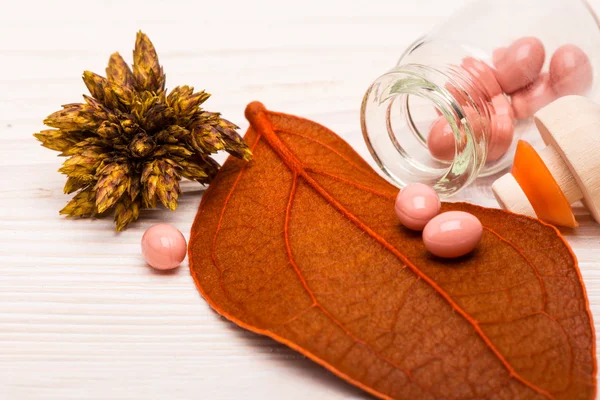 Alternativa píldoras de color rosa con hoja naranja —  Fotos de Stock