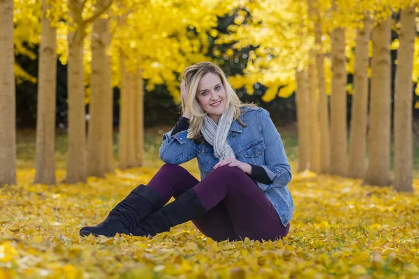 Hermosa modelo rubia posando en un campo de hojas amarillas — Foto de Stock