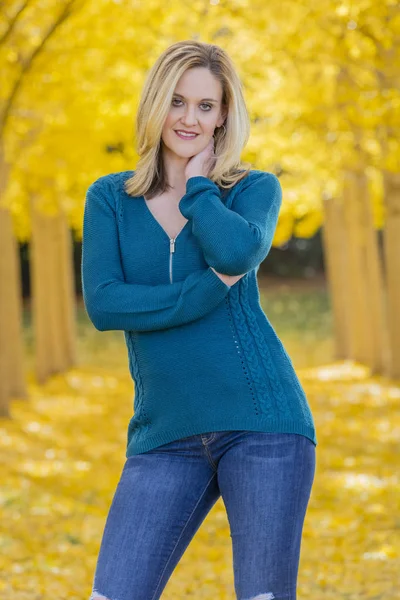 Belle blonde modèle posant dans un champ de feuilles jaunes — Photo
