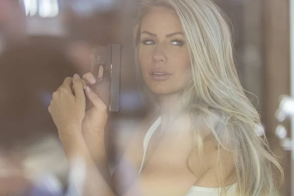 Superbe modèle blonde se protégeant avec un pistolet — Photo