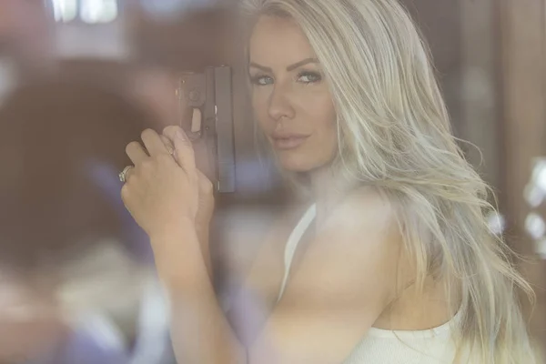 Gorgeous blond modell skydda sig själv med en Pistol — Stockfoto