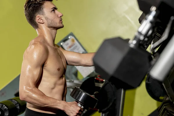 Mandlig atlet arbejder ud på en lokal gym - Stock-foto