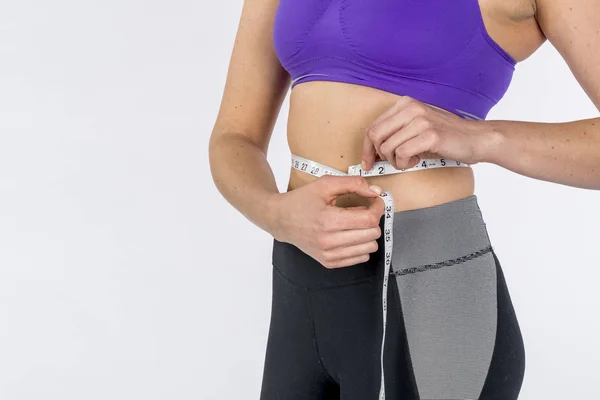 Heiße Brünette Fitness-Modell misst ihre Taille vor weißem Hintergrund — Stockfoto