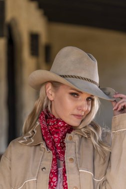 Kovboy gibi giyinmiş muhteşem sarışın bir manken. Açık havanın tadını çıkarıyor.