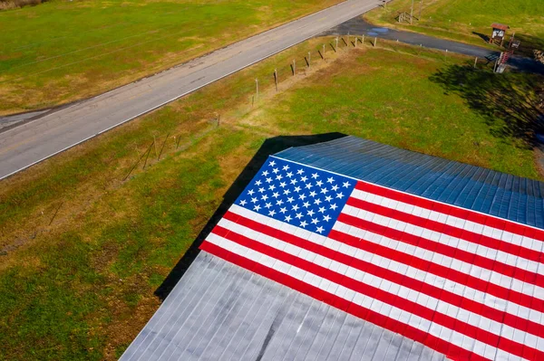 A country road with an American Flag painted on a barn near a farm in the United States