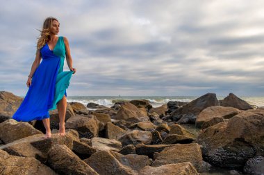 Güzel bir esmer İspanyol manken gün batımında sahilde poz veriyor.