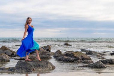 Güzel bir esmer İspanyol manken gün batımında sahilde poz veriyor.