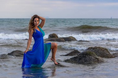 Güzel bir esmer İspanyol manken gün batımında sahilde poz veriyor.