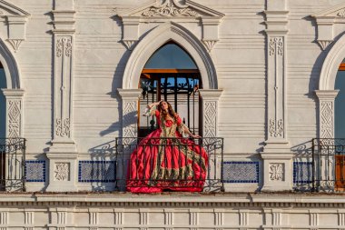 Muhteşem bir İspanyol esmer model ev ortamında geleneksel Meksika kıyafetleriyle poz veriyor.