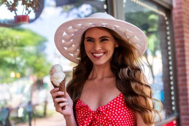 Güzel bir esmer model, şehir ortamında dondurma yerken dışarıda poz veriyor.