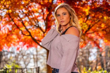 Muhteşem sarışın bir model parkta sonbahar gününün tadını çıkarıyor.