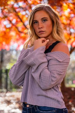 Muhteşem sarışın bir model parkta sonbahar gününün tadını çıkarıyor.