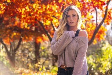Muhteşem sarışın bir model parkta sonbahar gününün tadını çıkarıyor.