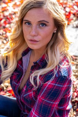 Muhteşem sarışın bir model parkta sonbahar gününün tadını çıkarıyor.