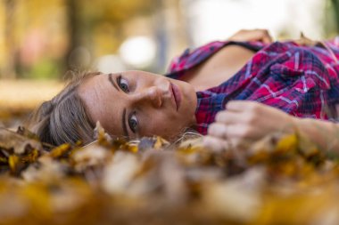 Muhteşem sarışın bir model parkta sonbahar gününün tadını çıkarıyor.